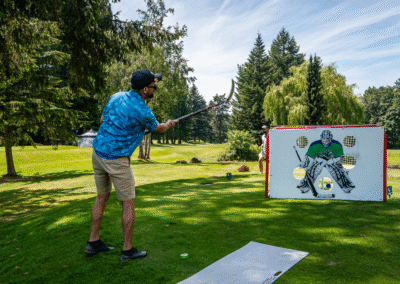 A man puts a golf towards a hockey net partially blocked by a poster