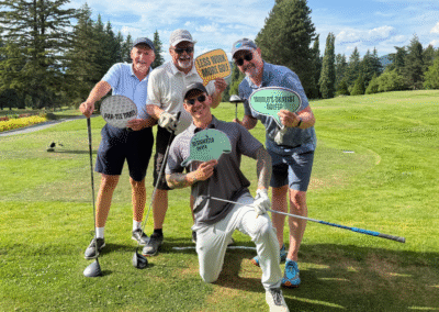 Abby News Staff pose holding Golf Themed posters.