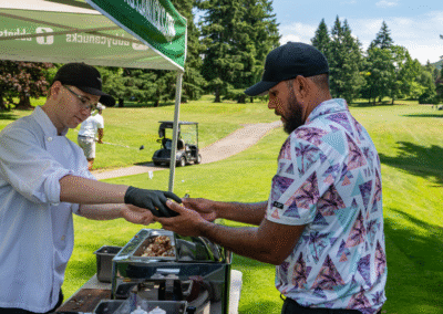 An employee of Prestige Phyiso massages a client's hand on the golf green at a booth